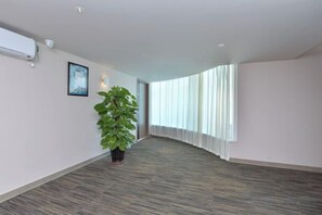 A spacious hallway with a potted plant, a framed picture on the wall, and a large window with curtains. - Jinjiang Inn Select (Sanyawan Jinjiling) (Sanya)