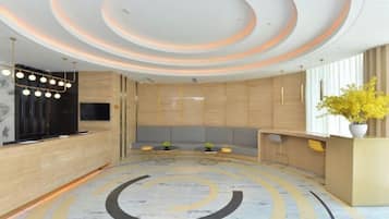 A modern reception area with a circular seating arrangement, a reception desk, and a decorative ceiling.