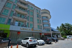A multi-story building with a prominent sign for 'JINHANG INK' on the ground floor. There are several parked cars in front of the building. - Jinjiang Inn Select (Sanyawan Jinjiling) (Sanya)
