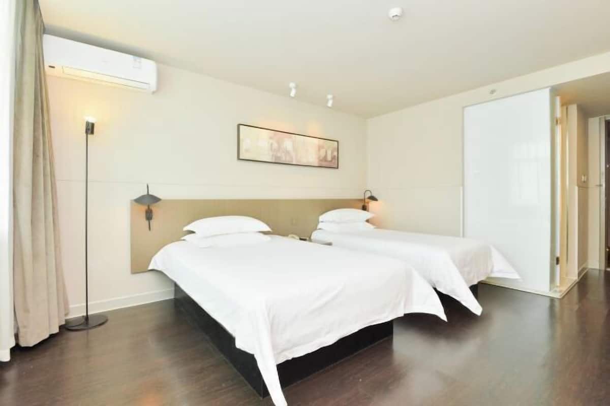 A hotel room with two beds, a large mirror, a painting on the wall, and a wardrobe.