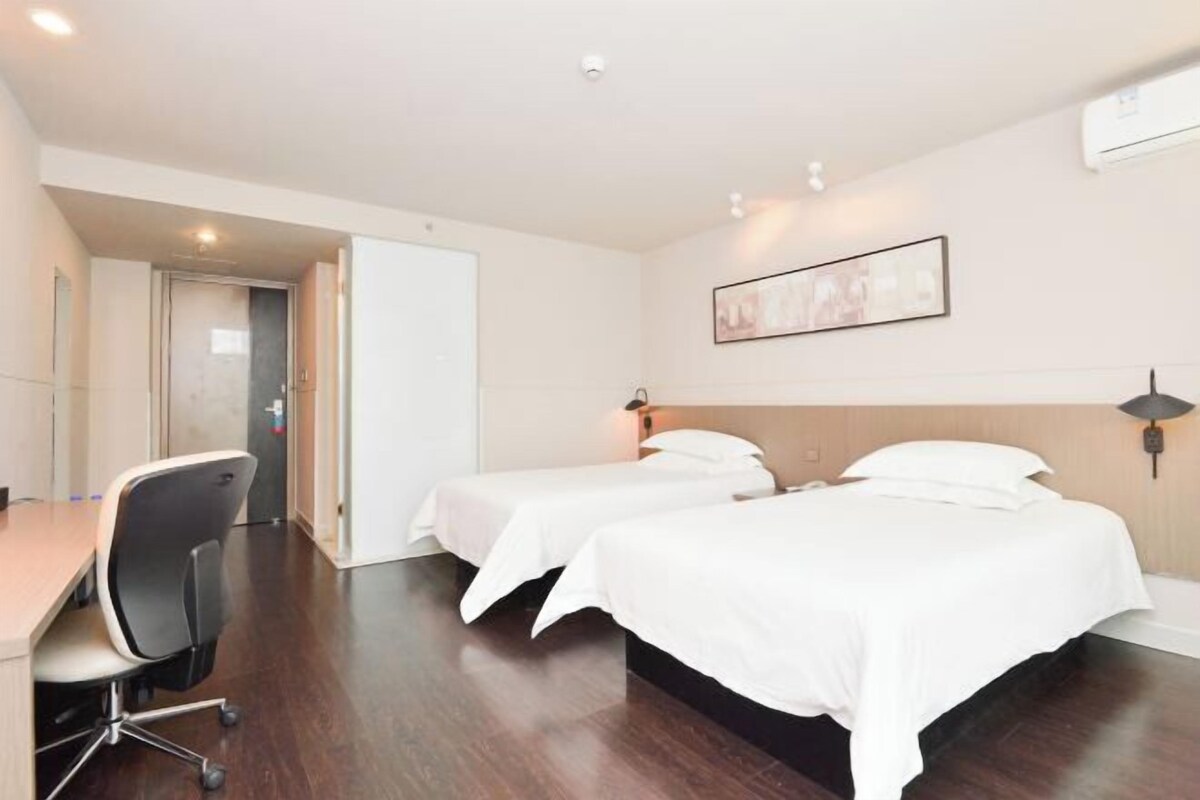 A hotel room with two beds, a desk, and a chair.
