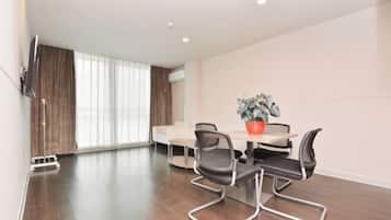 Quarto moderno com uma mesa de jantar, quatro cadeiras, um vaso de plantas e uma televisão de tela plana na parede.