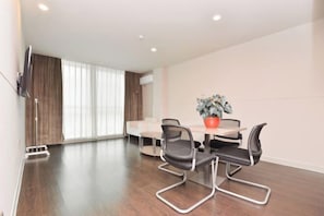 A modern room with a dining table, four chairs, a potted plant, and a flat-screen TV mounted on the wall. - Jinjiang Inn Select (Sanyawan Jinjiling) (Sanya)