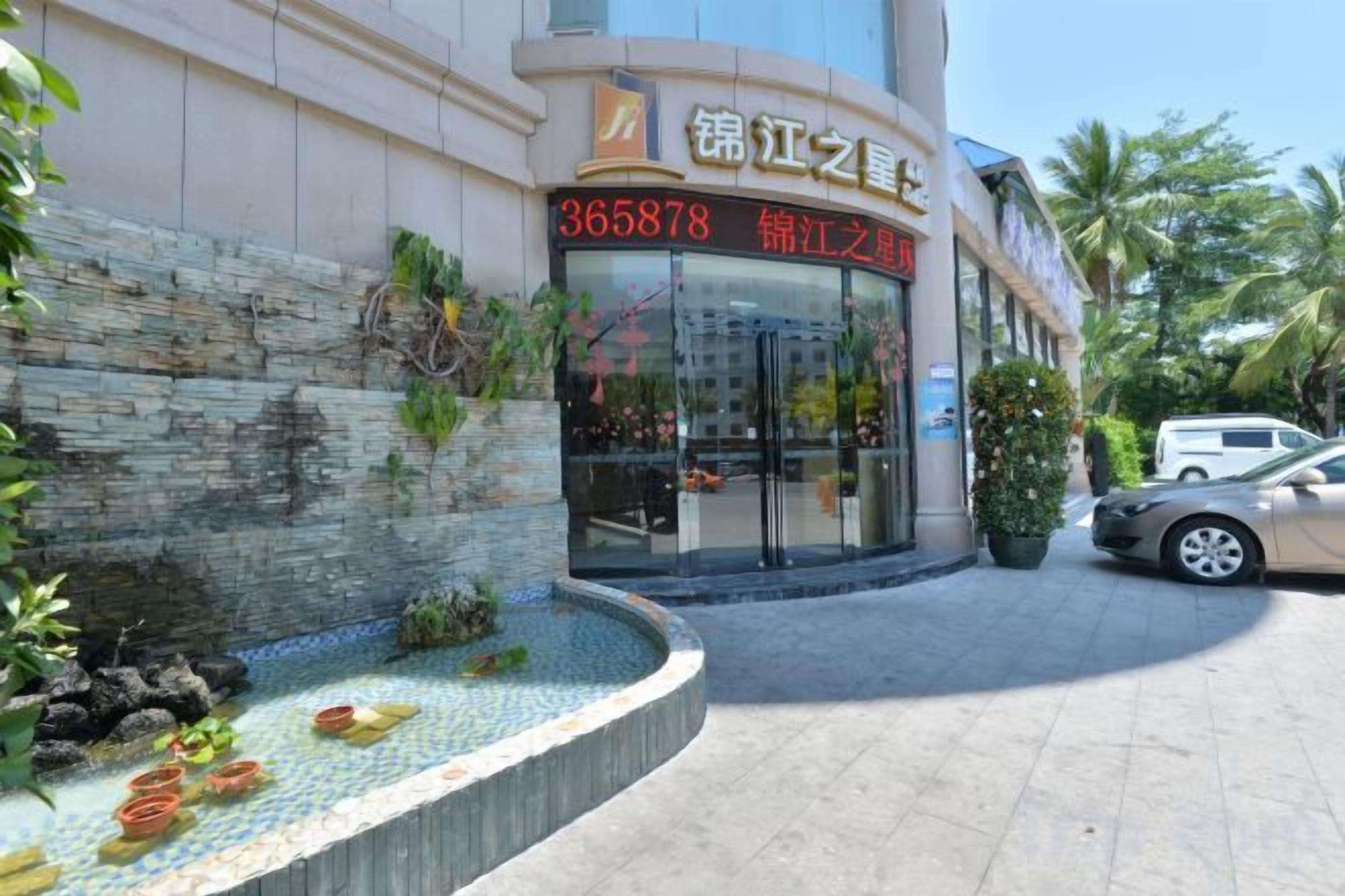 A building with a stone facade, a tiled entrance area, and a car parked in front.