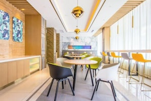 A modern interior with a bar area, seating, and a kitchen in the background.
