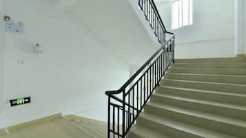 A staircase with black railings and beige steps in a building with white walls.