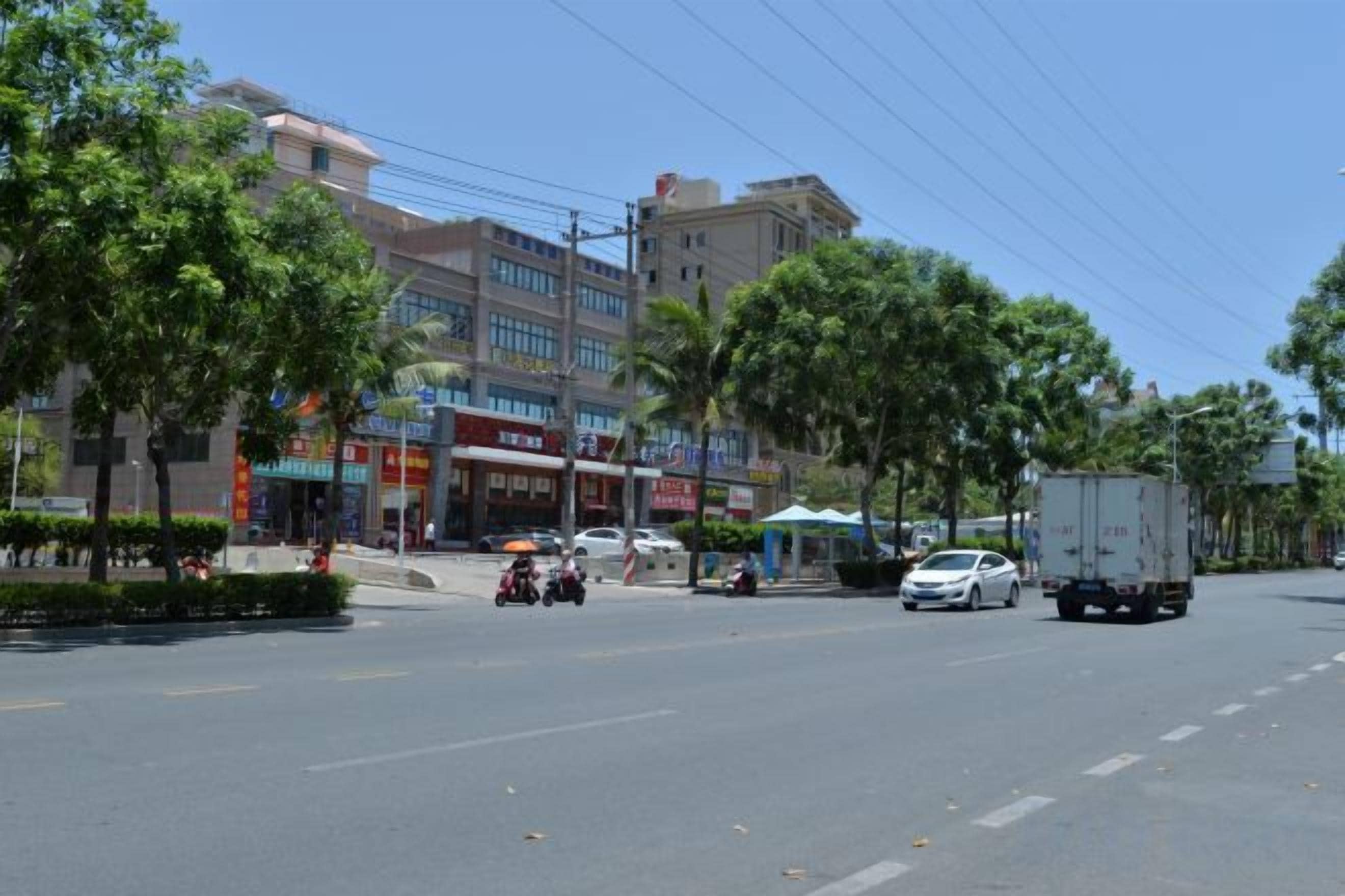 Une scène de rue avec des bâtiments, des arbres et des véhicules.