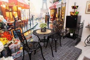 An outdoor café with tables and chairs, a potted plant, and a decorative lamp.