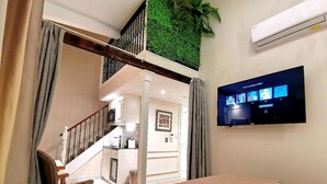 Une chambre d’hôtel avec un lit, une télévision, un escalier et un mur vert.