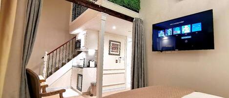 A hotel room with a bed, a TV, a staircase, and a green wall.