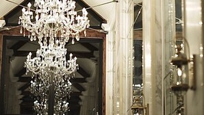 A grand chandelier in a hallway with an exit sign above a door.