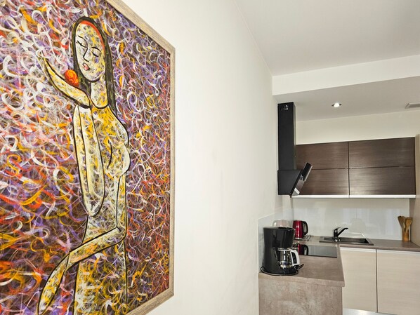 Una cocina moderna con cafetera, un hervidor rojo y un armario negro.