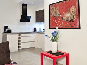A modern kitchen with a built-in oven, a coffee machine, and a red vase with flowers on a small table. - RS2.30 - Sienkiewicz Residence (RS1, RS2) (Swinoujscie)
