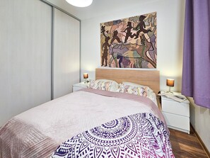 Un dormitorio moderno con una cama grande, dos mesitas de noche y una obra de arte colgada en la pared.