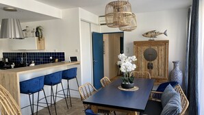 Une cuisine moderne avec un coin bar, une table à manger avec des chaises et un poisson décoratif accroché au mur.