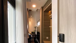 A modern hotel room with a wooden wardrobe, a desk with a chair, and a bed. - ST Signature Lite Tanjong Pagar - Dark (Singapore)