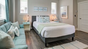 Ein Schlafzimmer mit einem Bett, Nachttischen, einer Couch und Kunstwerken an den Wänden.