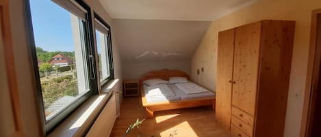 Un dormitorio pequeño con una cama individual, un armario de madera y una ventana que ofrece vistas al exterior.