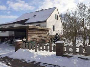Ein zweistöckiges Haus mit Garage, Holzzaun und einem schneebedeckten Garten.