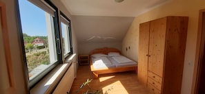 A small bedroom with a single bed, a wooden wardrobe, and a window providing a view of the outside. - Vacation Rental, Germany (Barth)