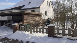 A two-story house with a garage, a wooden fence, and a snow-covered yard.
