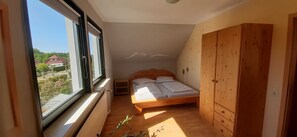 Une petite chambre à coucher avec un lit simple, une armoire en bois et une fenêtre donnant sur l’extérieur.