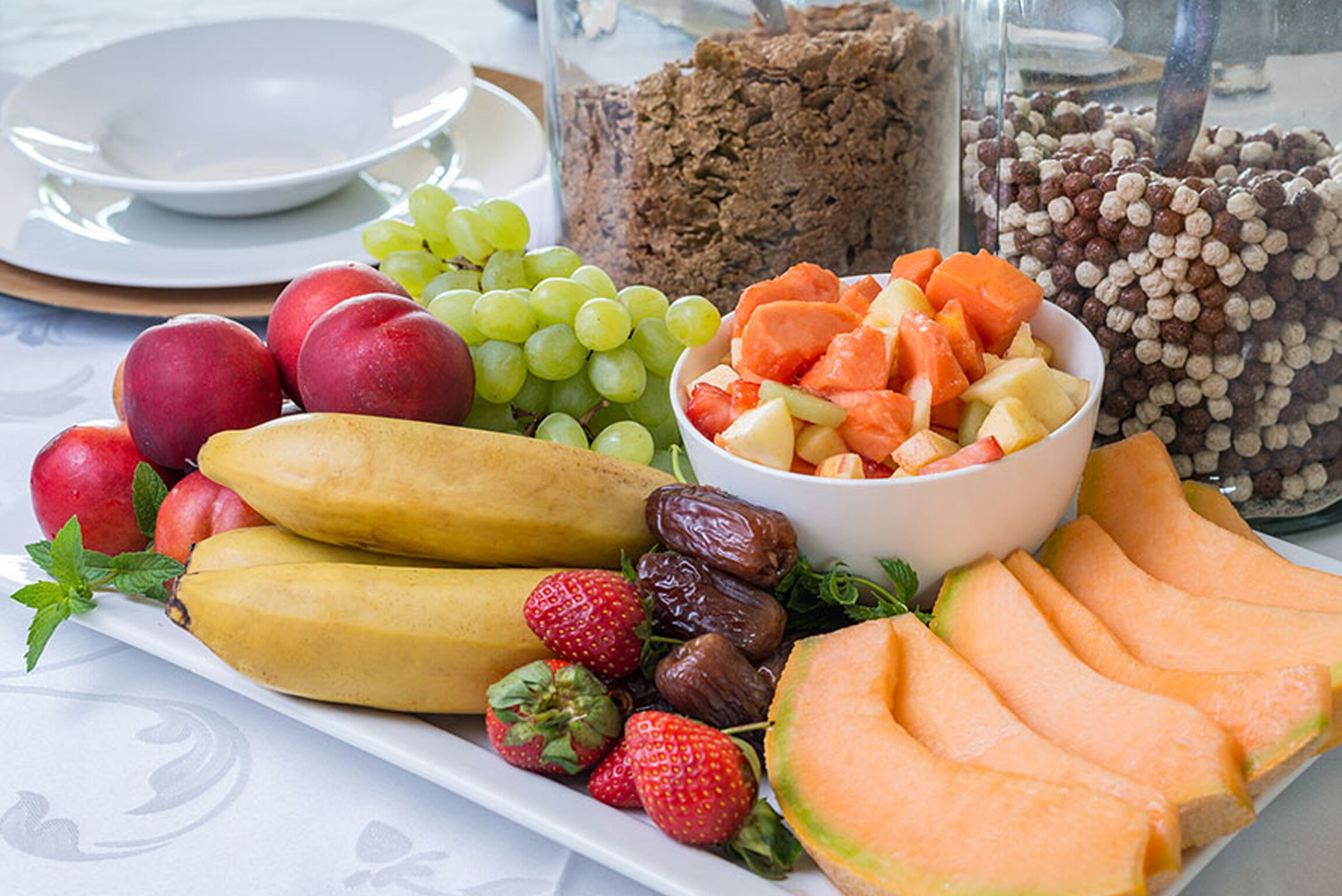 En fruktfat med olika sorters frukt och en skål med flingor.