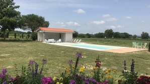 A poolside area with a covered seating area, a pool, and a garden with colorful flowers. - Authentic cottage in the countryside near Pau (Cescau)