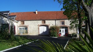 A stone building with a red-tiled roof, a gated entrance, and a paved driveway. - Authentic cottage in the countryside near Pau (Cescau)