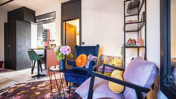 Een moderne woonkamer met een blauwe bank, een klein bijzettafeltje met een bloevas en een boekenkast tegen de muur.