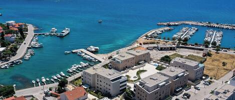 A coastal town with modern buildings, a marina with boats, and a clear view of the sea.