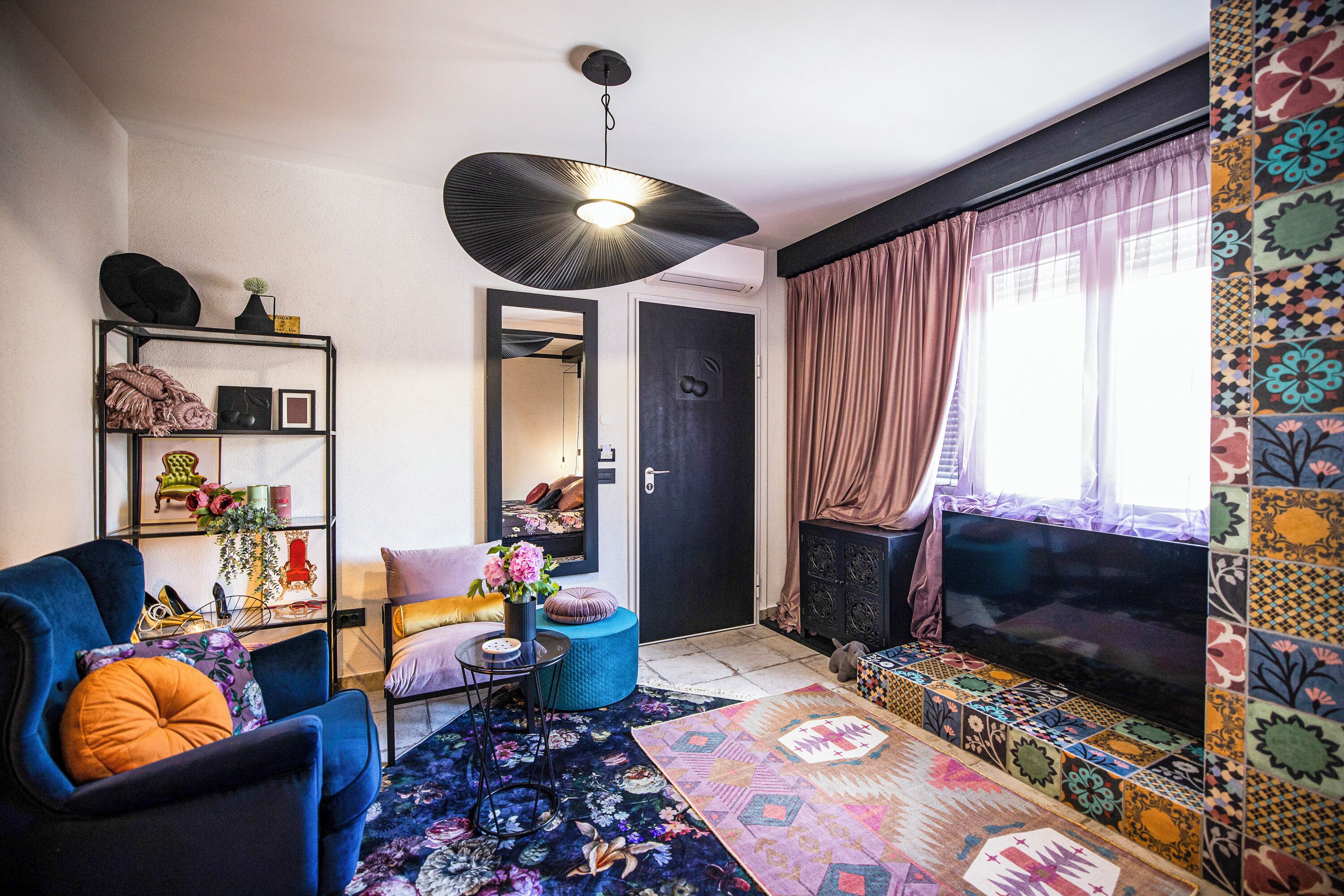 A living room with a sofa, a coffee table, a TV, a bookshelf, and a patterned rug.
