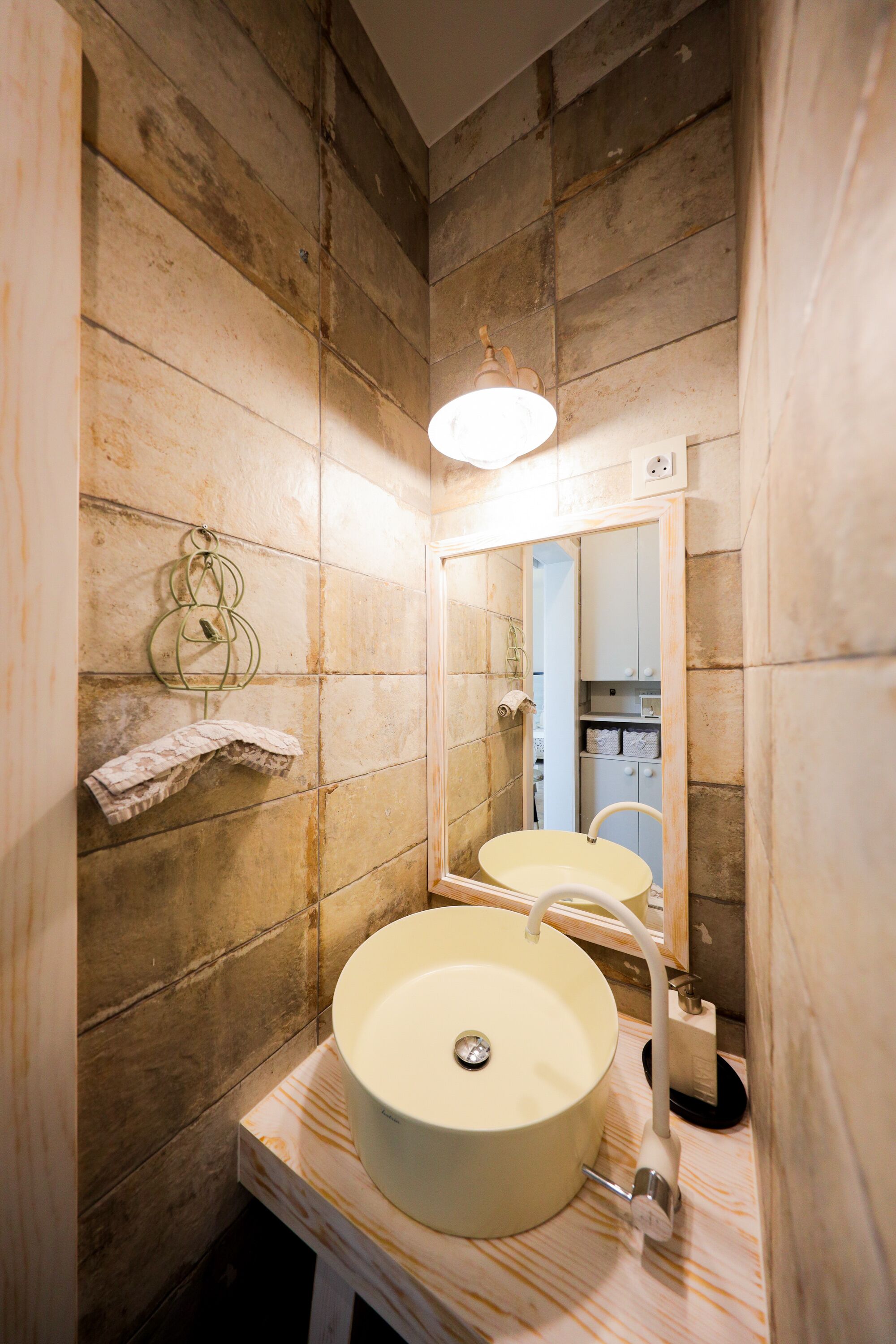 A bathroom with a round sink, a mirror, and a towel rack.