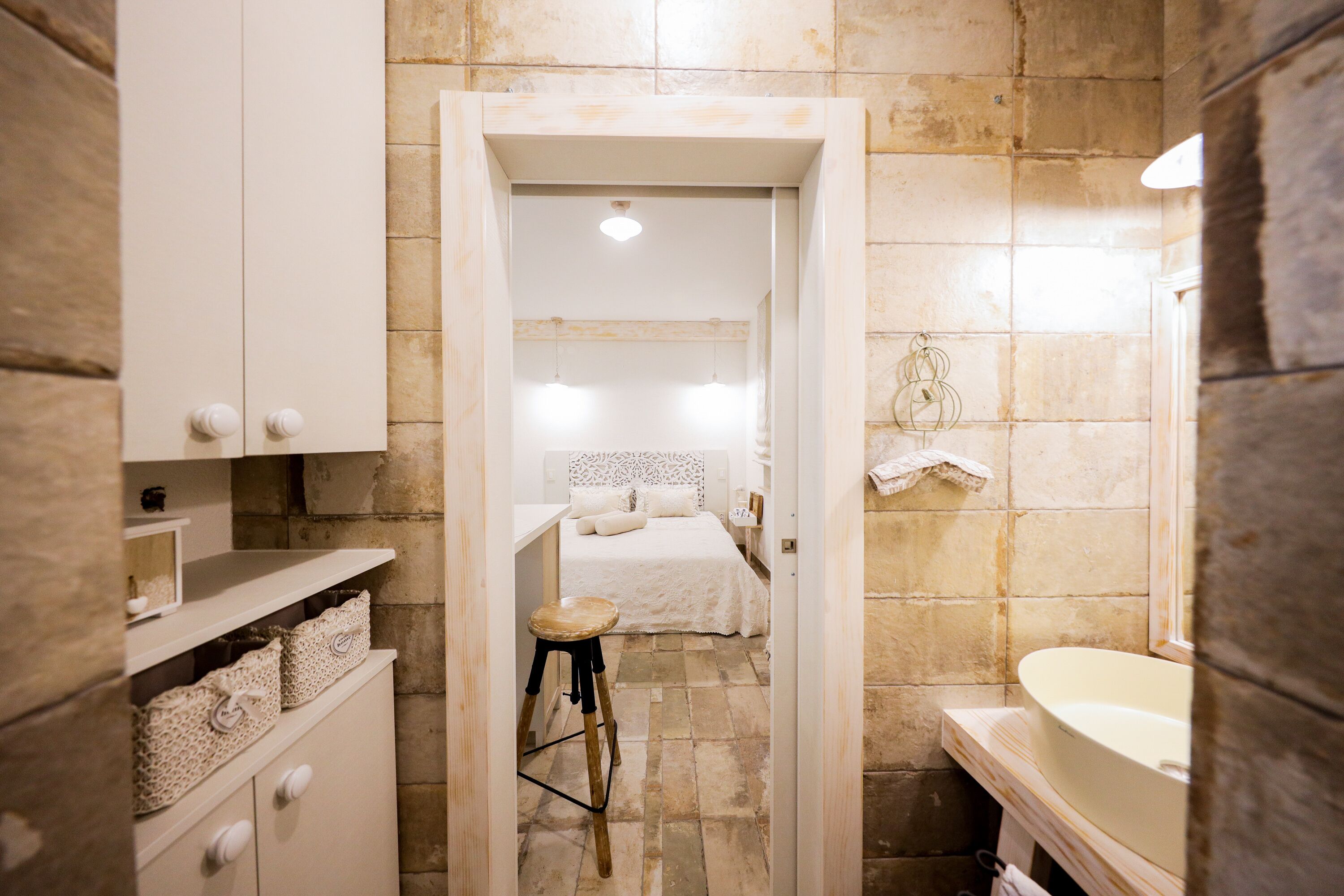 A bathroom with a sink, mirror, and a small stool.