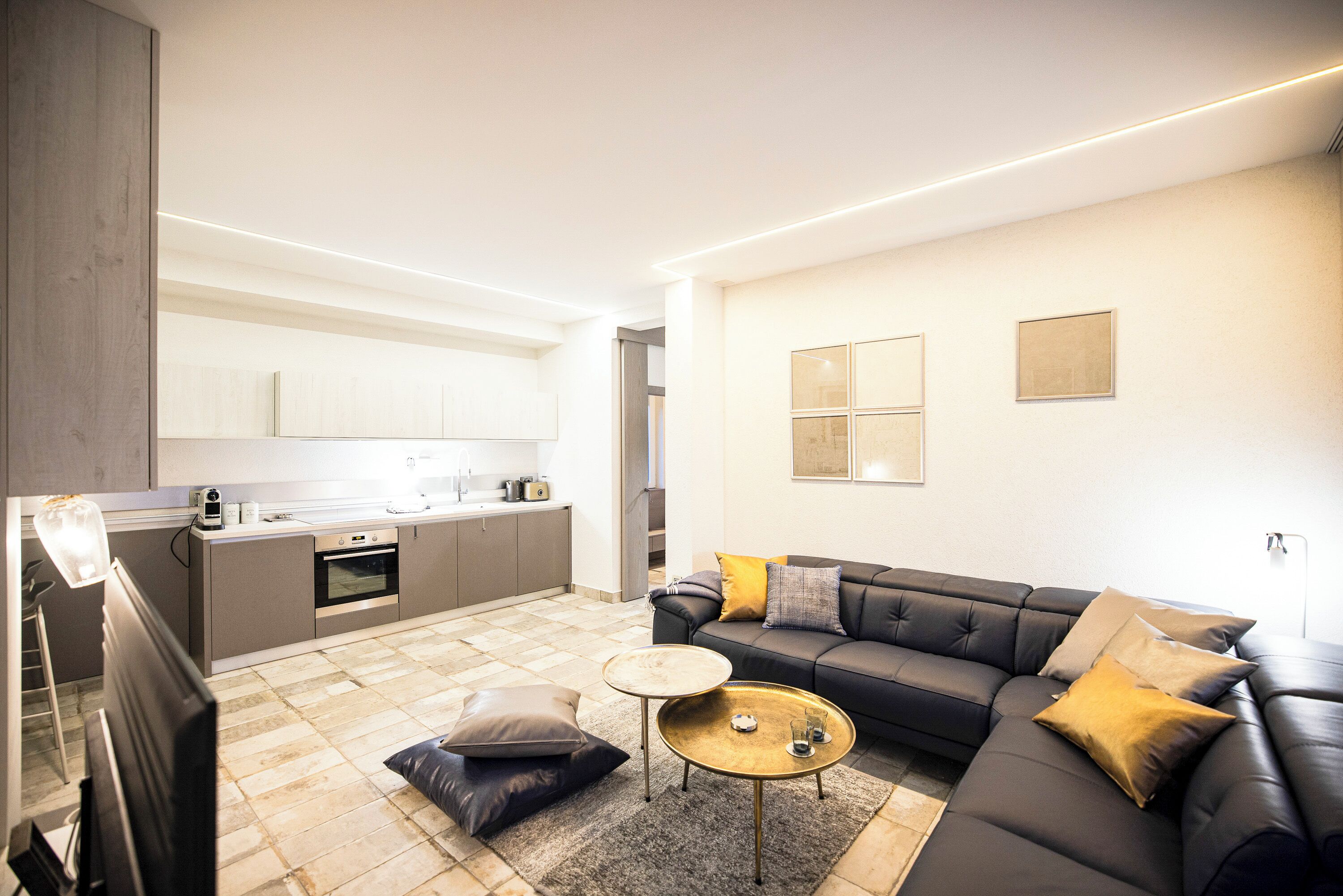 A modern living room with a sofa, coffee table, and a kitchen area in the background.