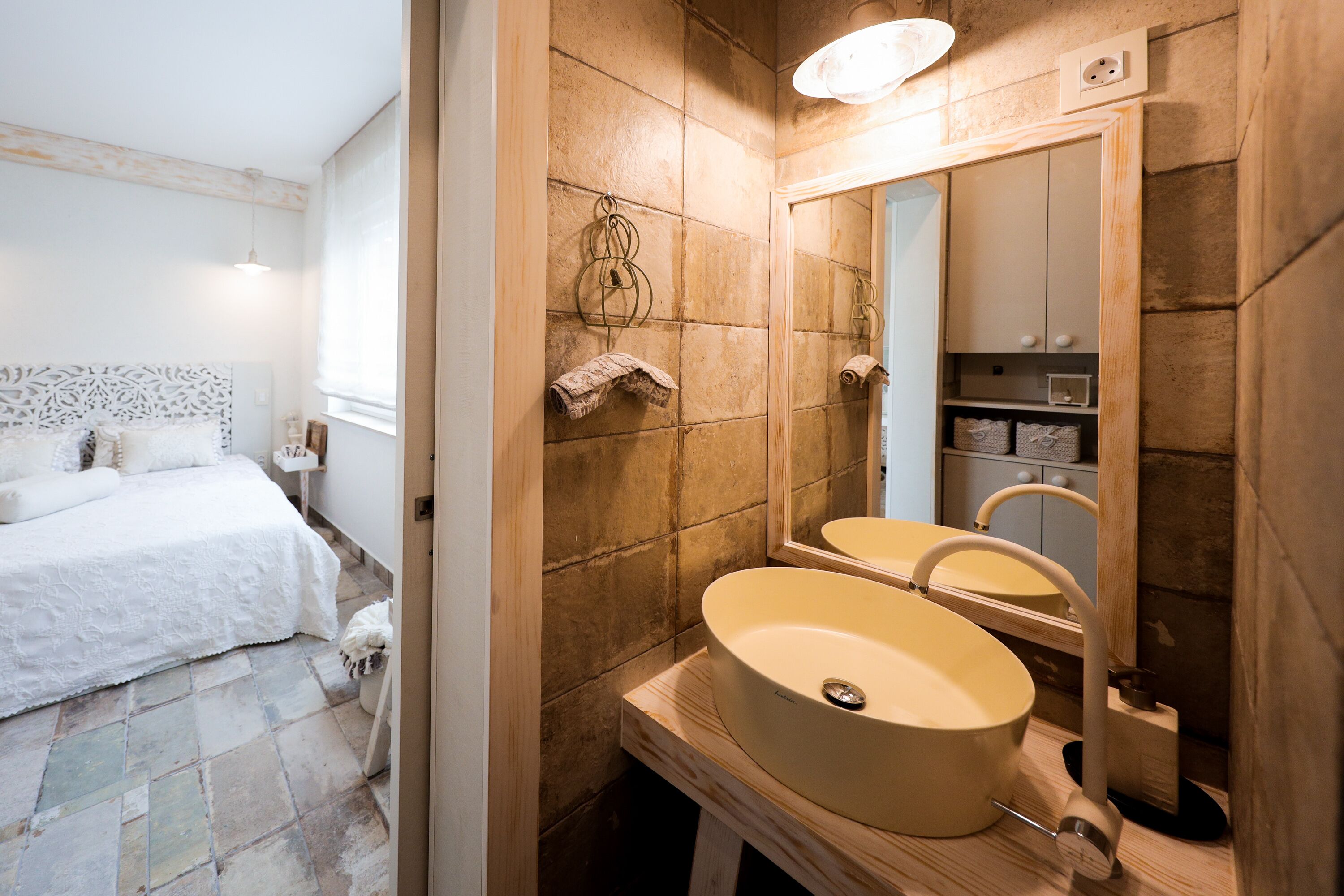 Un baño con un espejo grande, un lavamanos color beige y un mueble de tocador de madera.