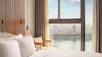 A hotel room with a large bed, a view of a cityscape through a window, and a city skyline visible in the distance.