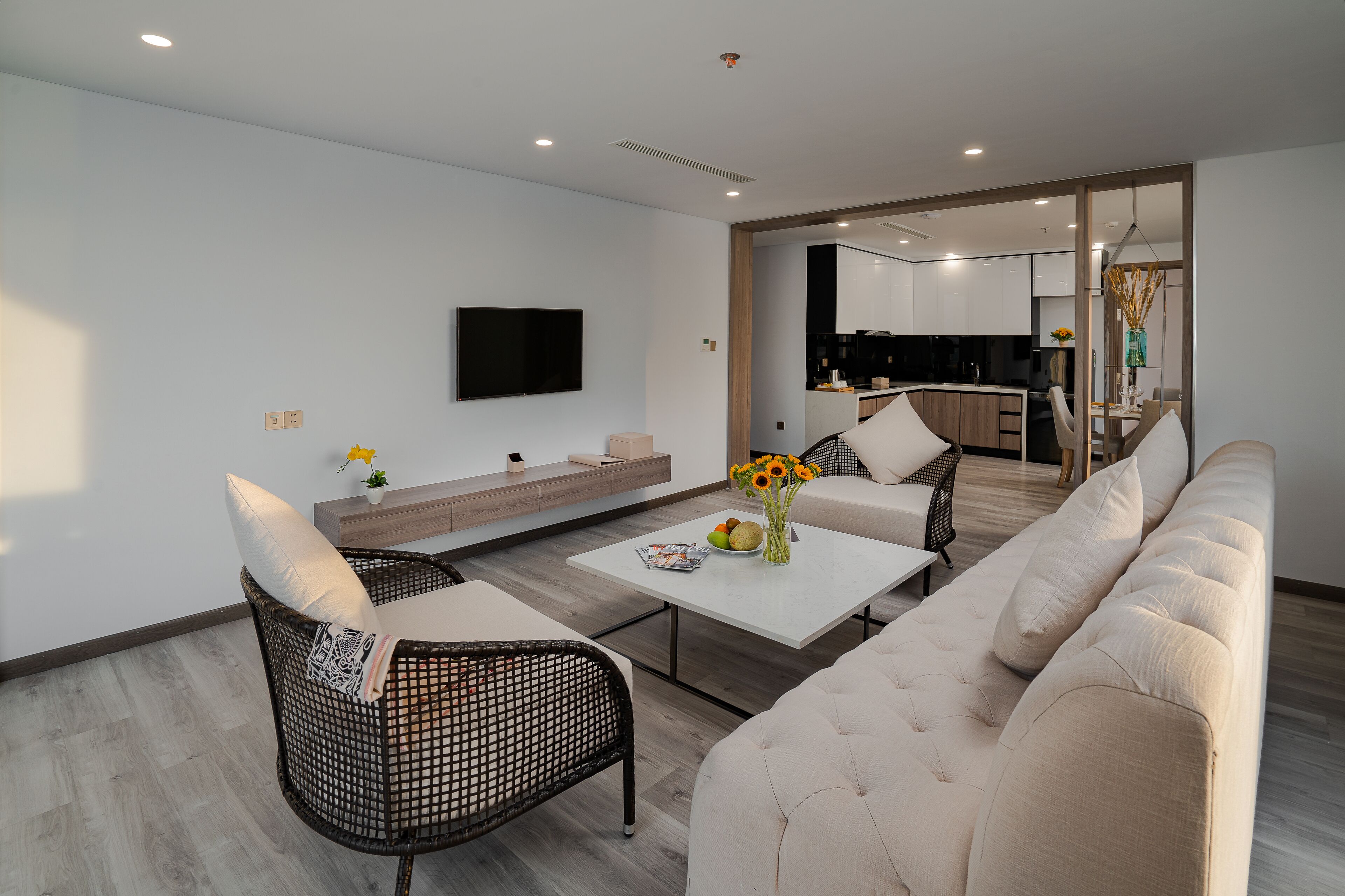 A modern living room with a sofa, two armchairs, a coffee table, and a flat-screen TV mounted on the wall.
