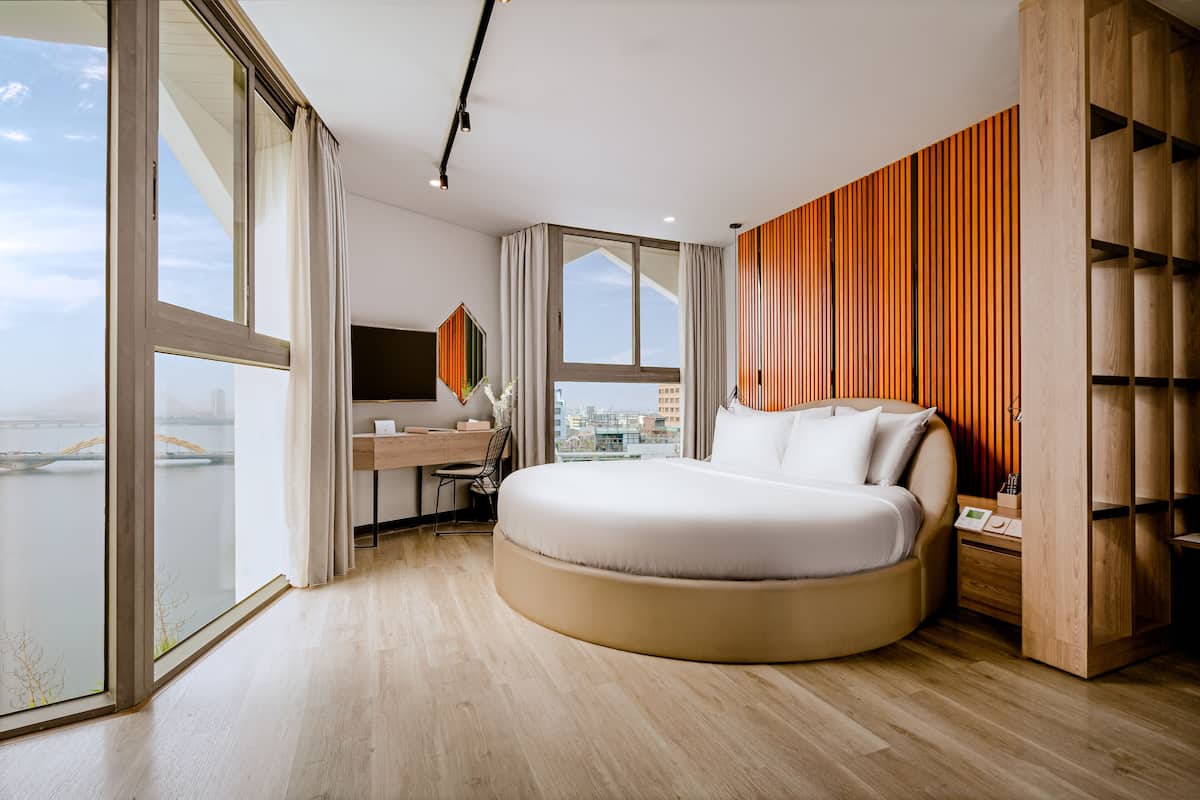 Quarto moderno com uma cama grande, uma escrivaninha e vista para a cidade.