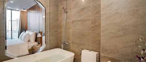 A modern bathroom with a large mirror, a bathtub, a toilet, and a shower.