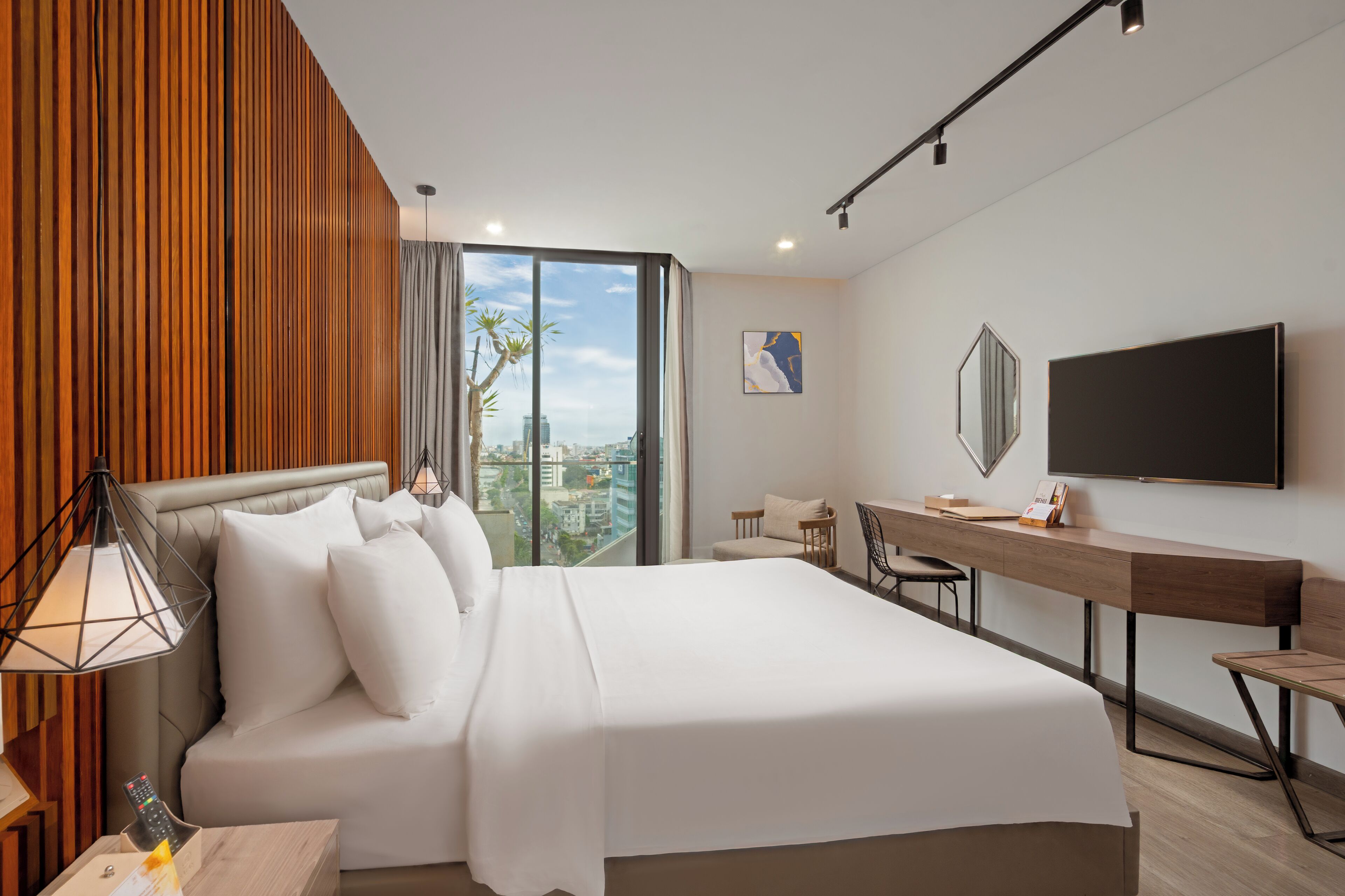 A modern hotel room with a large bed, a desk, and a TV.