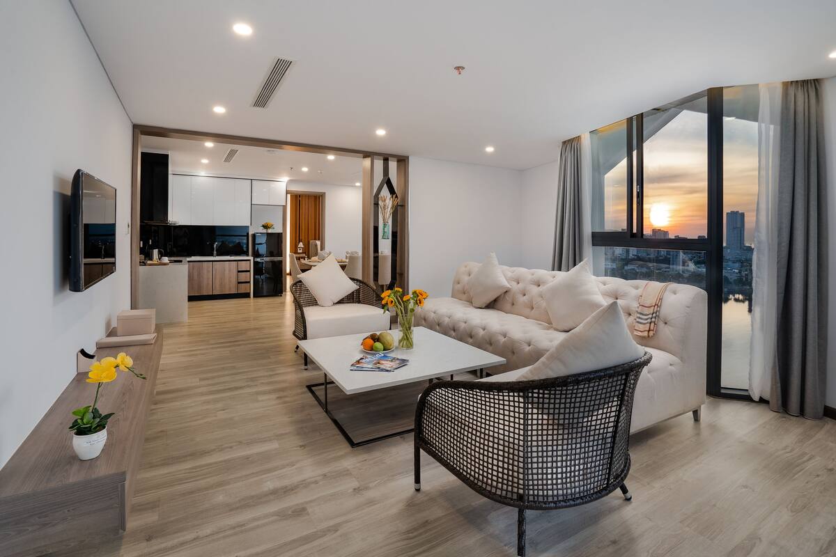 Uma sala de estar moderna com sofá, mesa de centro e uma área de jantar ao fundo.