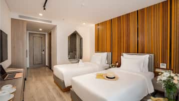 Habitación de hotel con dos camas, un escritorio con una computadora portátil, un televisor y un panel de pared de madera.