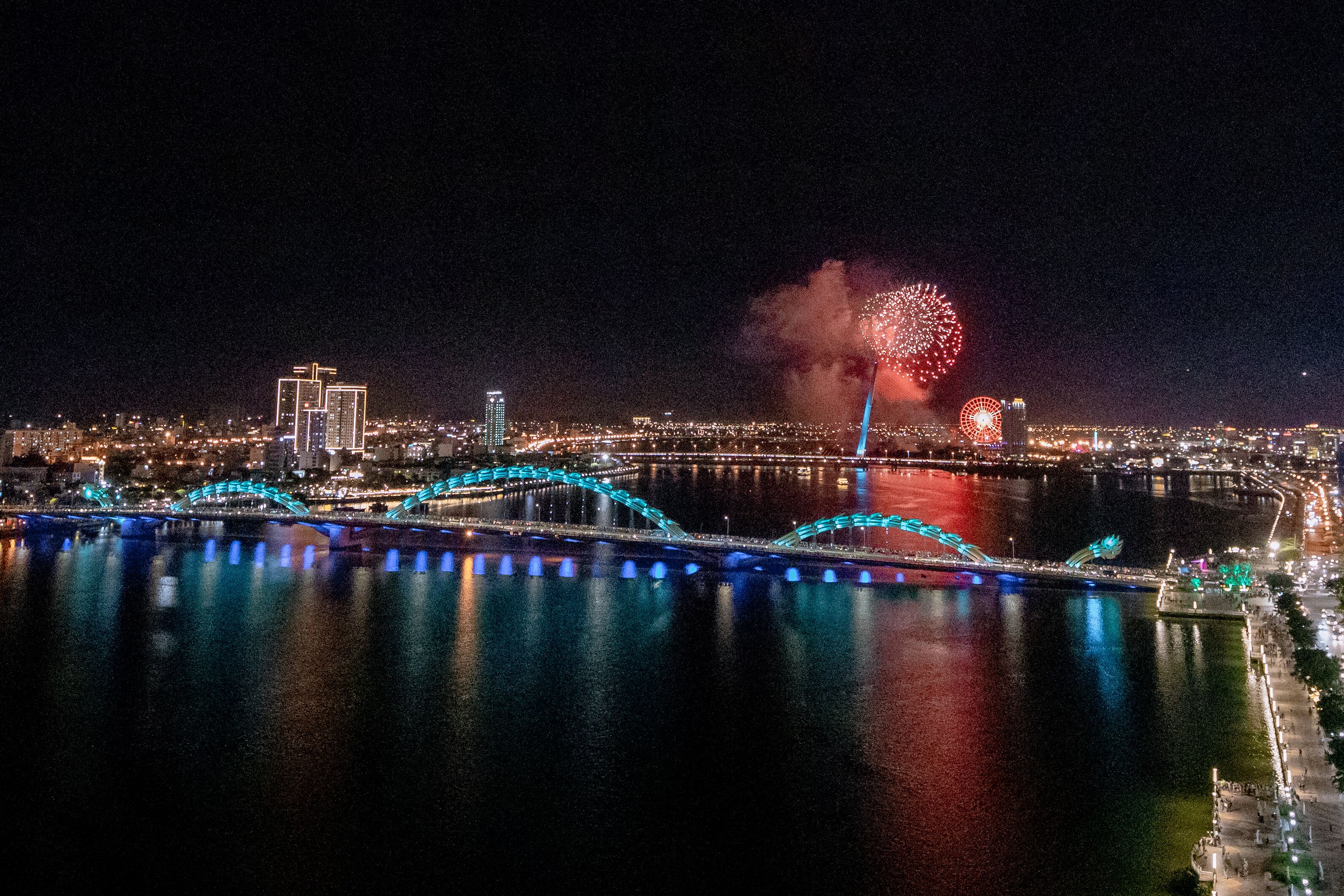 A nighttime cityscape with illuminated bridges and fireworks.