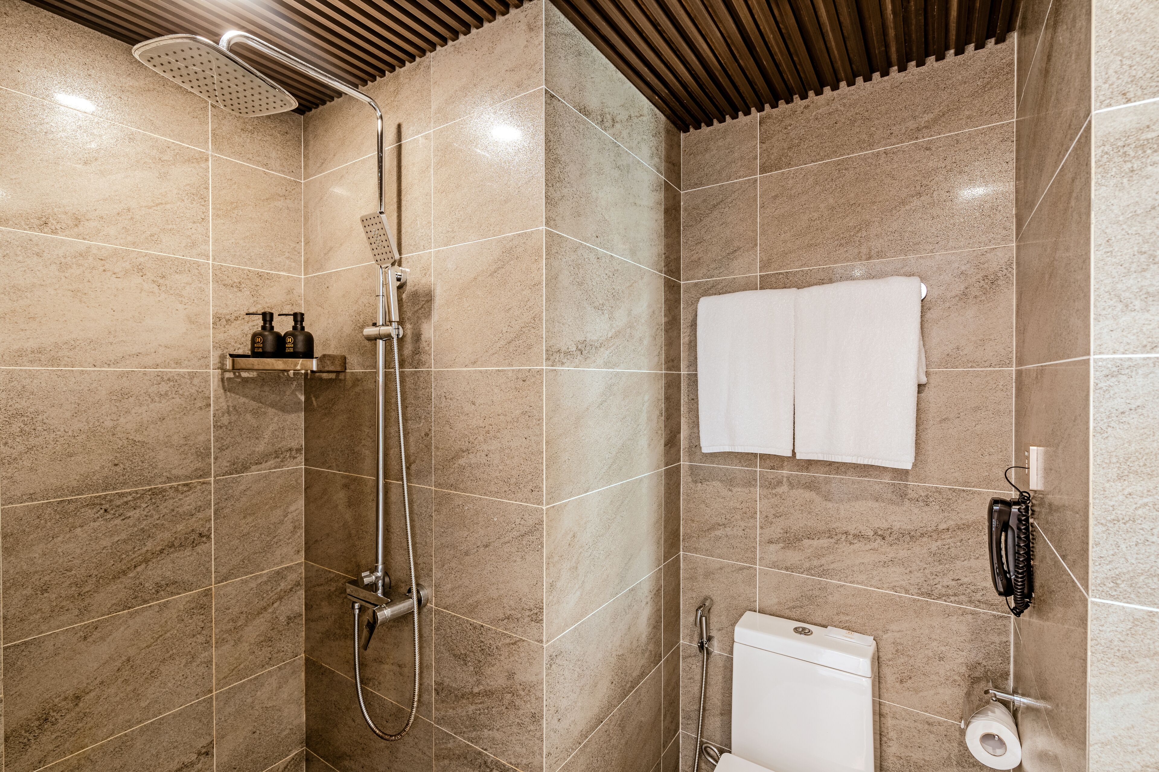 A modern bathroom with a shower, toilet, and towel rack.