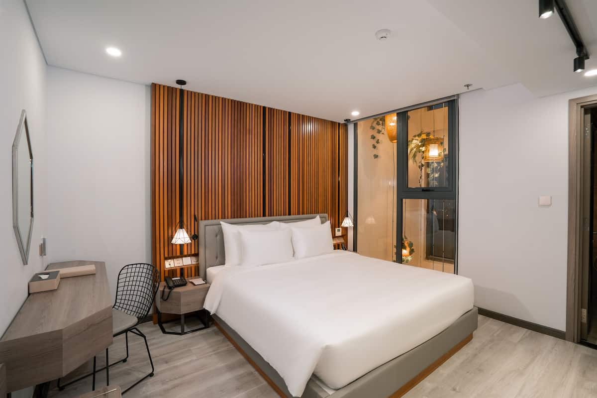Quarto moderno com cama grande, escrivaninha e uma cadeira.