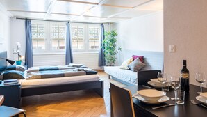A modern bedroom with a bed, a desk, and a dining area. - ZH Niederdorf II - Hitrental Apartment (Zürich)