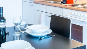 A modern kitchen with a dining table set for two, featuring a bottle of wine, glasses, and plates. - ZH Niederdorf II - Hitrental Apartment (Zürich)