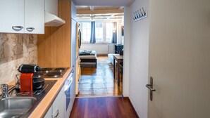 A narrow kitchen with a wooden floor, white cabinets, a stove, and a sink. - ZH Niederdorf II - Hitrental Apartment (Zürich)