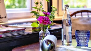 Ein Tisch mit einer Lampe, einer Wasserflasche, einem Glas und einer Vase mit Blumen.